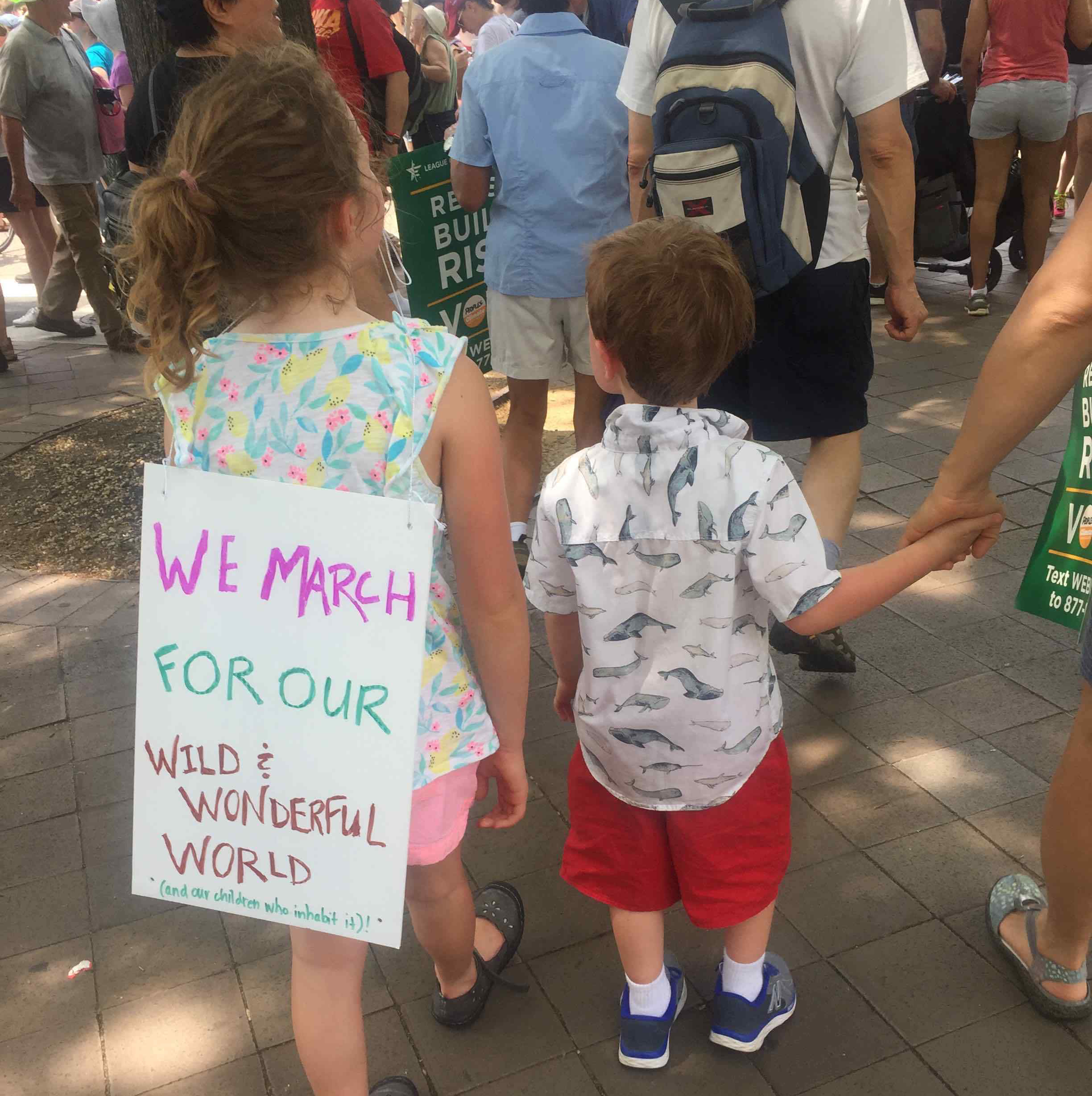 Photo: Two kids walking, one with a sign saying "We march for our wild and wonderful world."