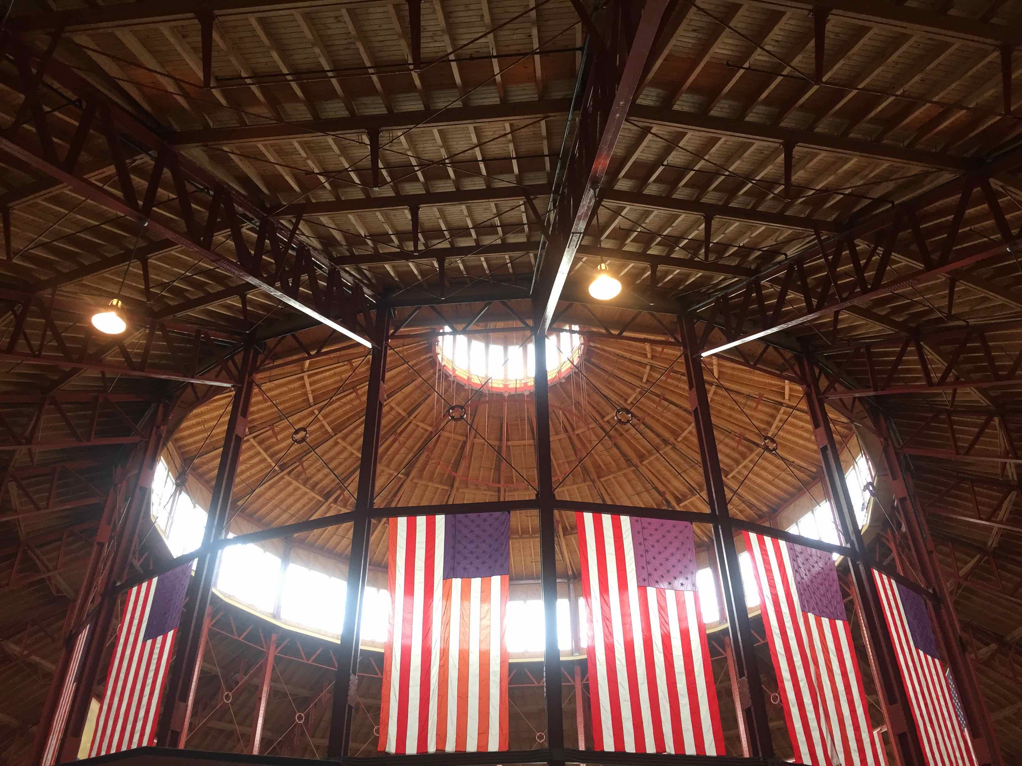 Photo: The roundhouse of a former train station looking up. Windows around the top letting in the sun, surrounded by American flags hanging from the ceiling.